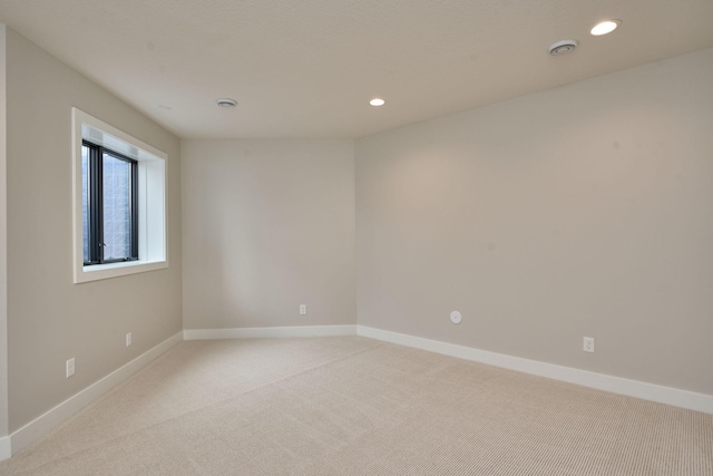 spare room with recessed lighting, light colored carpet, and baseboards