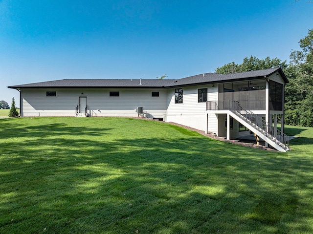 rear view of property with stairway, a yard, and a sunroom