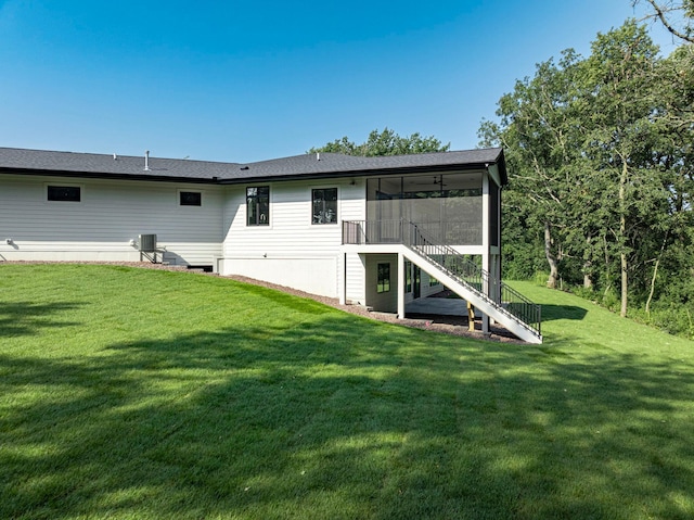 rear view of house featuring stairs, a yard, and a sunroom