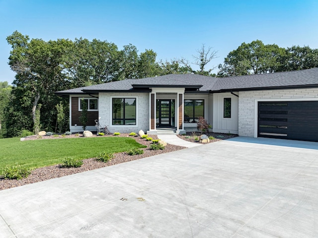 view of front of house featuring board and batten siding, a shingled roof, a front lawn, driveway, and an attached garage