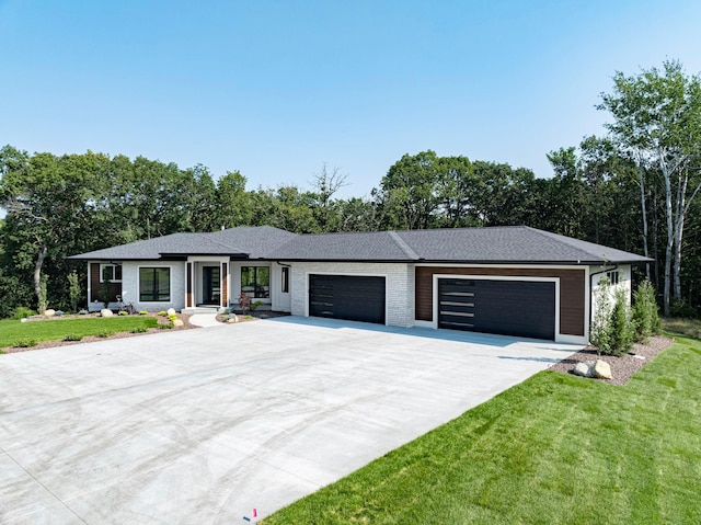 view of front of home with brick siding, driveway, a front lawn, and an attached garage