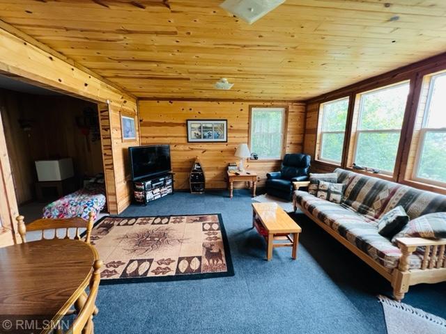 living room with wood ceiling and dark colored carpet