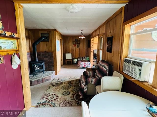 living room featuring a wood stove, light colored carpet, and wooden walls