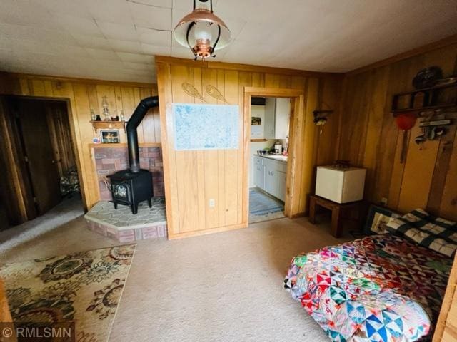 bedroom with a wood stove, ensuite bath, light carpet, and wood walls