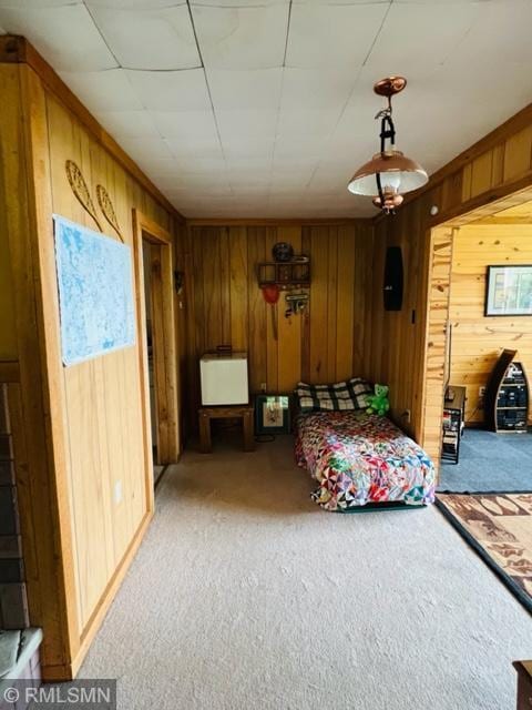 bedroom with light colored carpet and wood walls