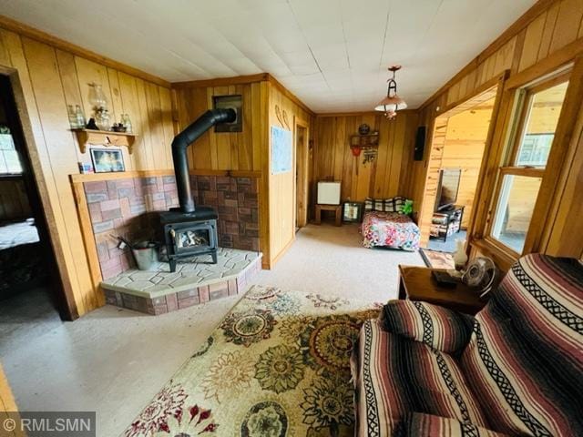 living room with a chandelier, wood walls, and a wood stove