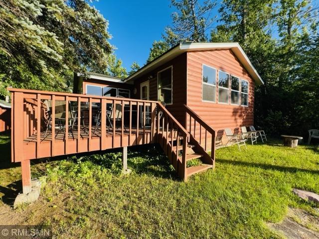 rear view of property with a wooden deck and a lawn