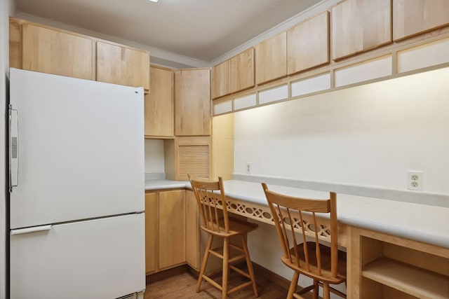 kitchen with light countertops, freestanding refrigerator, wood finished floors, and light brown cabinetry