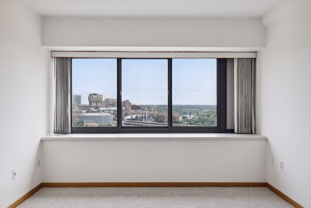 unfurnished room with a city view, carpet, and baseboards
