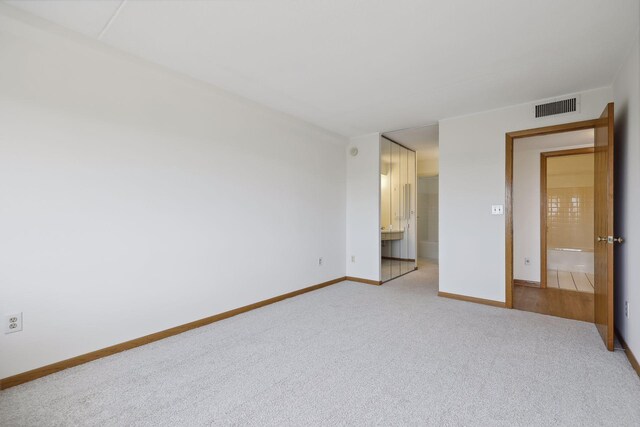 unfurnished bedroom featuring visible vents, light colored carpet, baseboards, and connected bathroom
