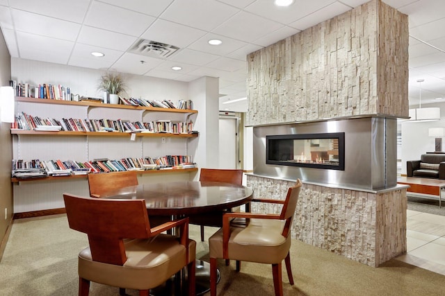 dining space with a glass covered fireplace, visible vents, a paneled ceiling, and carpet floors