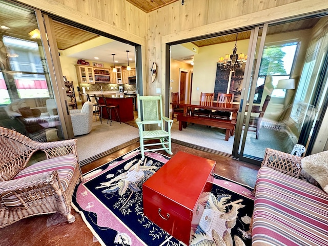 living room featuring carpet flooring, an inviting chandelier, and wooden walls