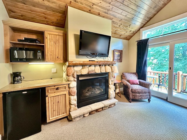 living room with lofted ceiling, a stone fireplace, light colored carpet, and wooden ceiling