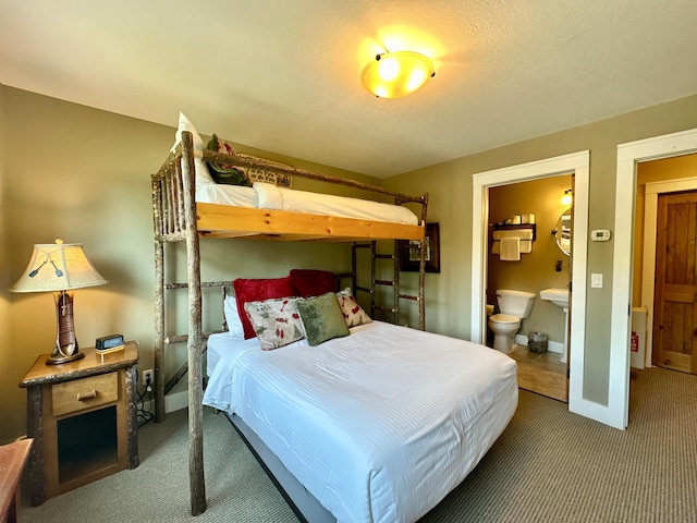 carpeted bedroom with a textured ceiling and connected bathroom