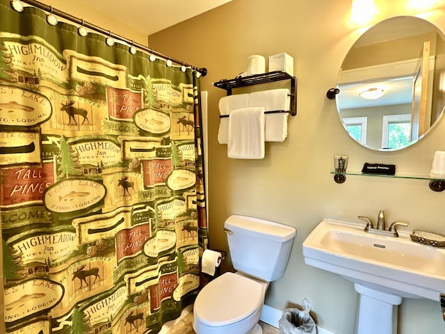 bathroom with toilet, sink, and a shower with shower curtain