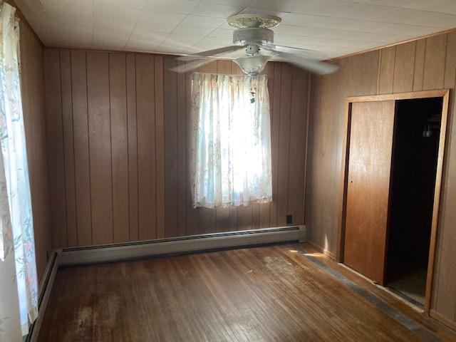 interior space with wooden walls, dark wood-type flooring, and a closet