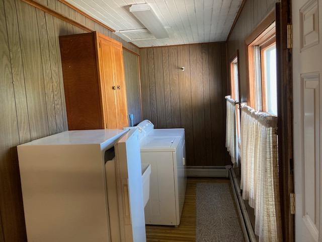 clothes washing area featuring wood ceiling, wood walls, light wood-type flooring, cabinets, and washer and clothes dryer