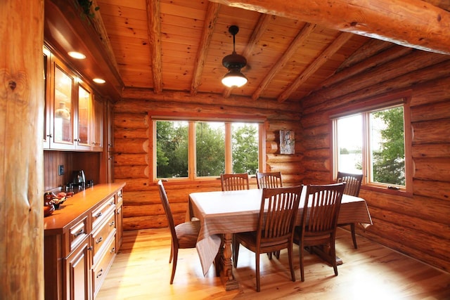 dining area with light hardwood / wood-style flooring, rustic walls, and wooden ceiling