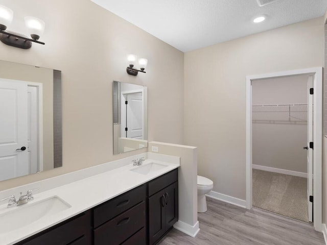 full bath featuring a sink, a spacious closet, toilet, and double vanity