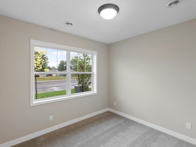 carpeted spare room featuring visible vents and baseboards