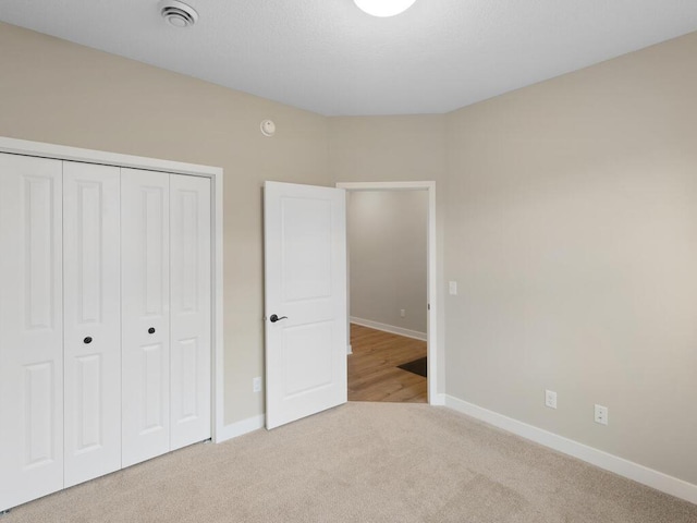 unfurnished bedroom with light carpet, baseboards, and a closet