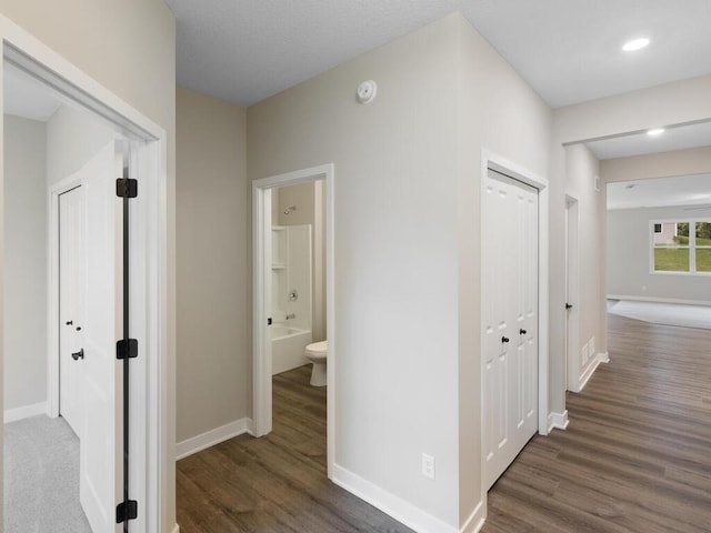 hallway featuring dark wood-type flooring and baseboards