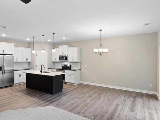 kitchen featuring stainless steel appliances, pendant lighting, white cabinets, and a sink