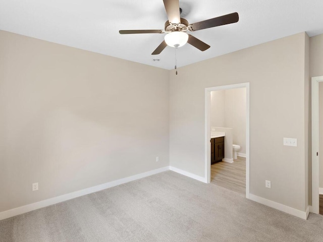 unfurnished bedroom featuring a ceiling fan, light carpet, connected bathroom, and baseboards