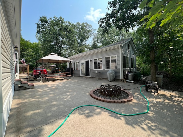 view of patio featuring a wooden deck, a gazebo, and a fire pit