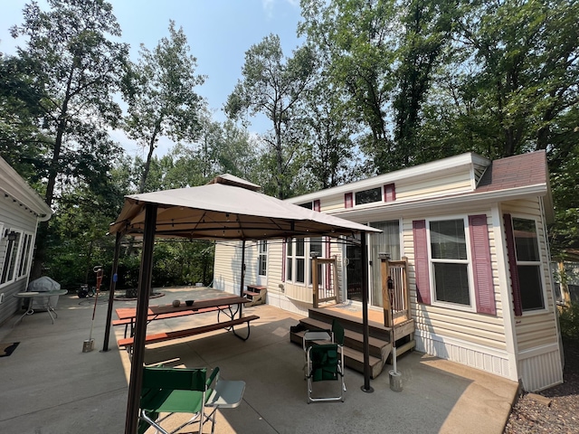 rear view of house with a deck, a gazebo, a patio area, and a hot tub