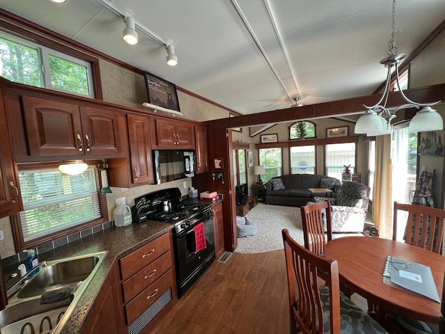 kitchen featuring black gas range, dark hardwood / wood-style floors, sink, rail lighting, and pendant lighting