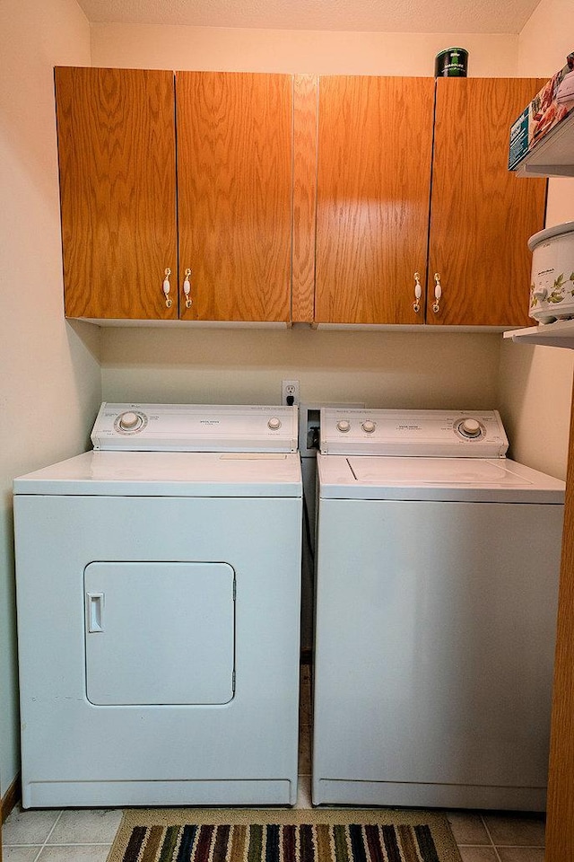 washroom with hookup for a washing machine, washing machine and dryer, light tile floors, and cabinets