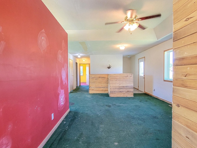 unfurnished bedroom with baseboards, dark carpet, and ceiling fan