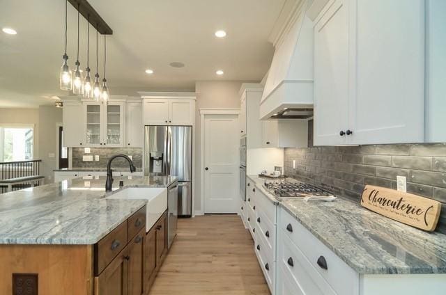 kitchen featuring light hardwood / wood-style floors, tasteful backsplash, white cabinetry, custom range hood, and sink