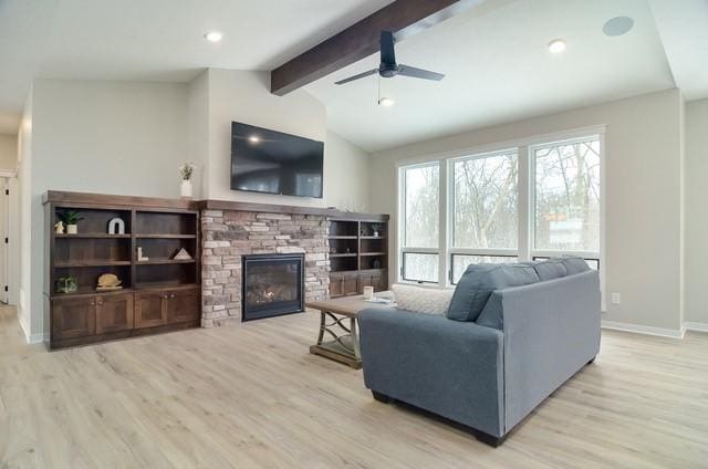 living room featuring a stone fireplace, light hardwood / wood-style floors, ceiling fan, and lofted ceiling with beams