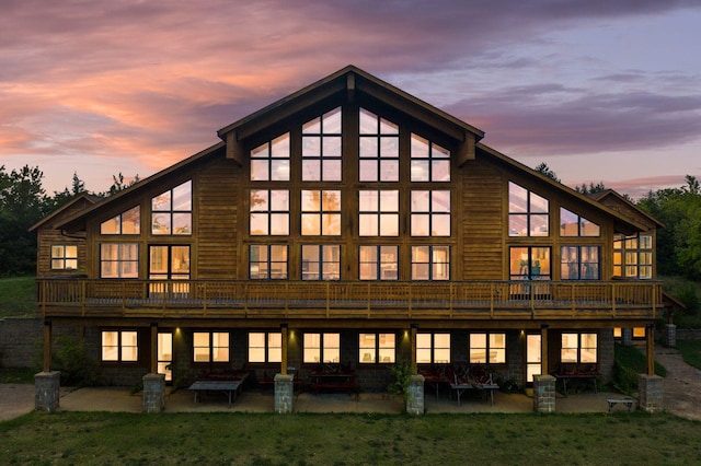 back house at dusk featuring a yard and a patio