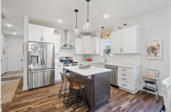 kitchen with stainless steel appliances, dark hardwood / wood-style flooring, backsplash, a center island, and wall chimney exhaust hood