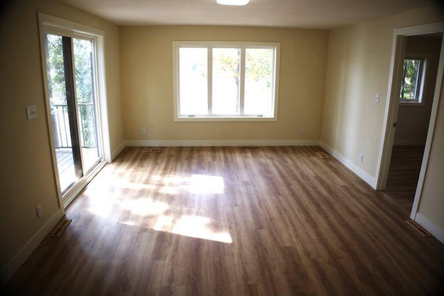 spare room featuring dark wood-type flooring and a healthy amount of sunlight