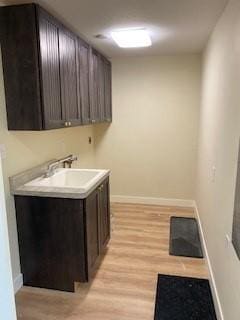 washroom with sink, light hardwood / wood-style flooring, and cabinets