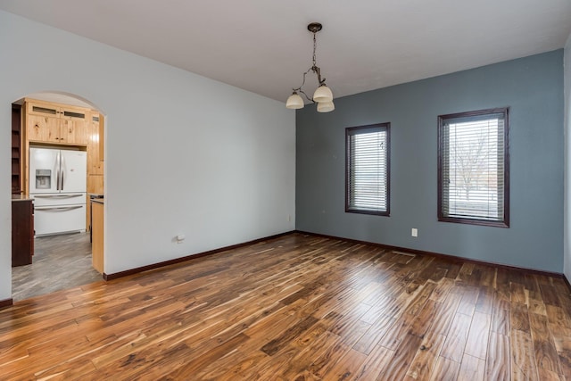 spare room featuring dark hardwood / wood-style floors and a chandelier