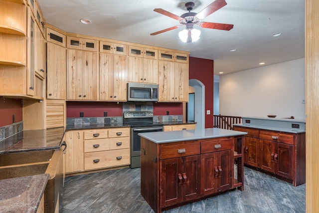 kitchen with dark hardwood / wood-style floors, ceiling fan, a kitchen island, and appliances with stainless steel finishes