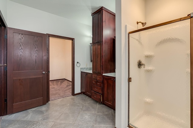 bathroom with a shower with shower door, vanity, and tile floors