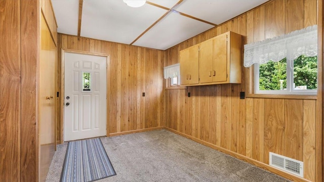 doorway with light colored carpet and wooden walls