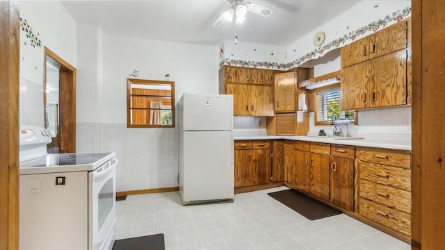 kitchen featuring white appliances, backsplash, light tile patterned floors, ceiling fan, and tile walls