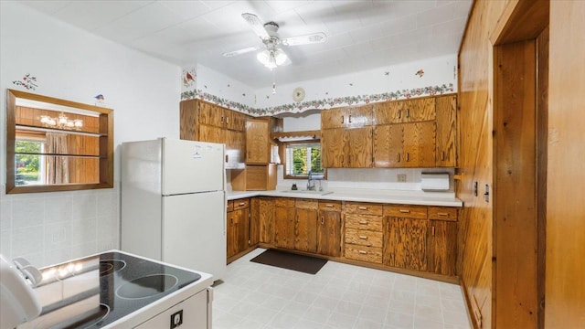 kitchen featuring light tile patterned floors, white refrigerator, sink, black stove, and ceiling fan