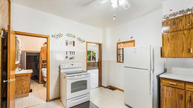 kitchen with tile walls, white appliances, ceiling fan, and light tile patterned flooring