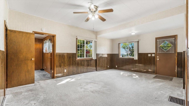 unfurnished room with wood walls, ceiling fan, and carpet flooring