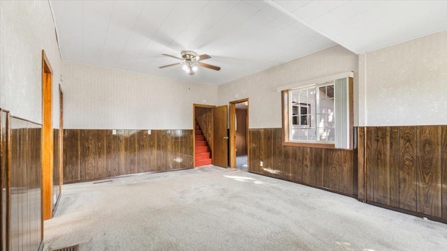 spare room featuring wood walls, ceiling fan, and carpet floors