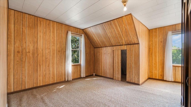 additional living space with wood walls, carpet floors, and vaulted ceiling