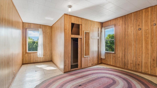 unfurnished bedroom featuring multiple windows, wood walls, and light tile patterned flooring